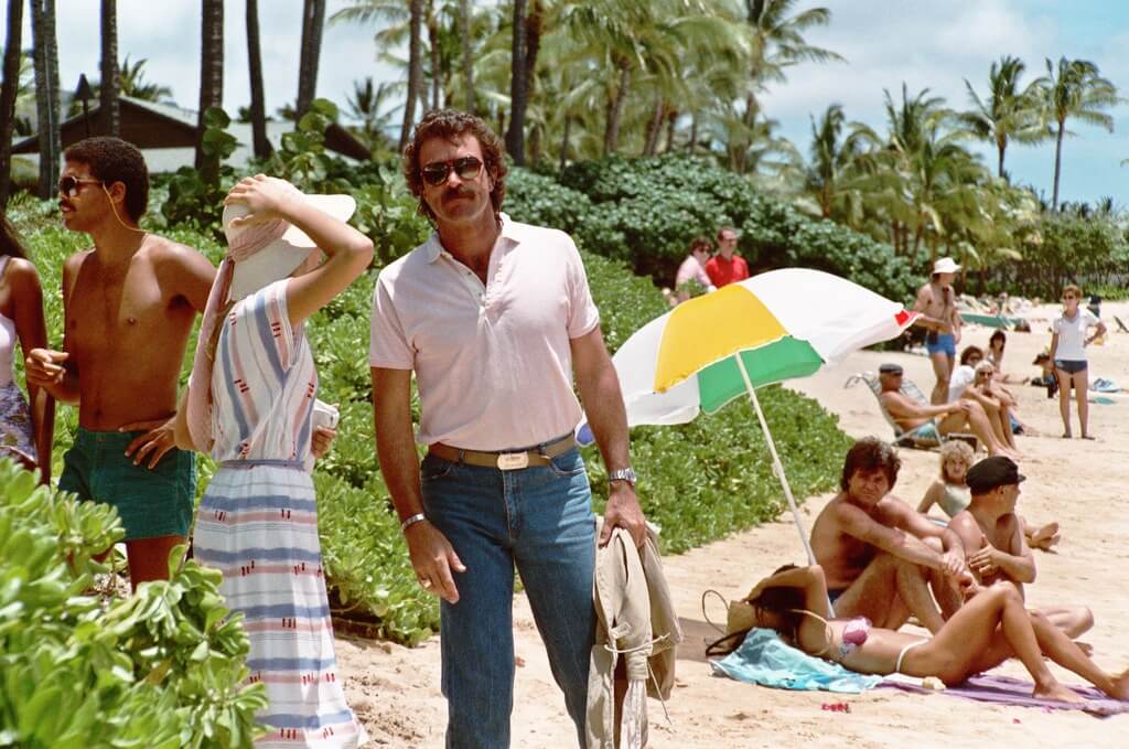 Tom Selleck stands on a beach.
